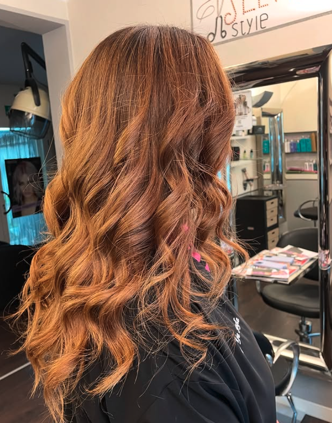 Capelli lunghi ondulati con meches caramello nel salone